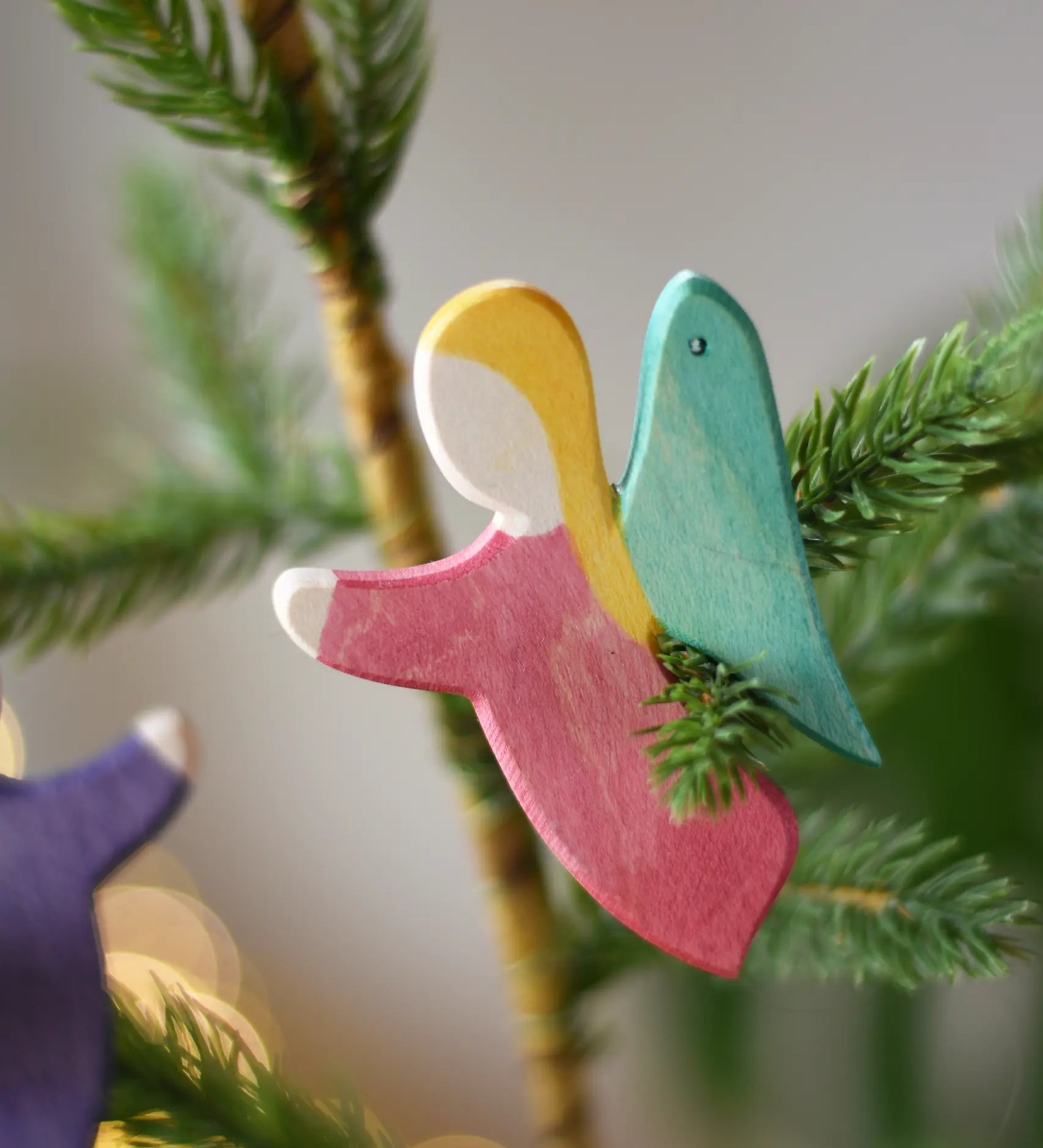 Ostheimer red angel wooden handmade decoration placed on a Christmas tree branch. 