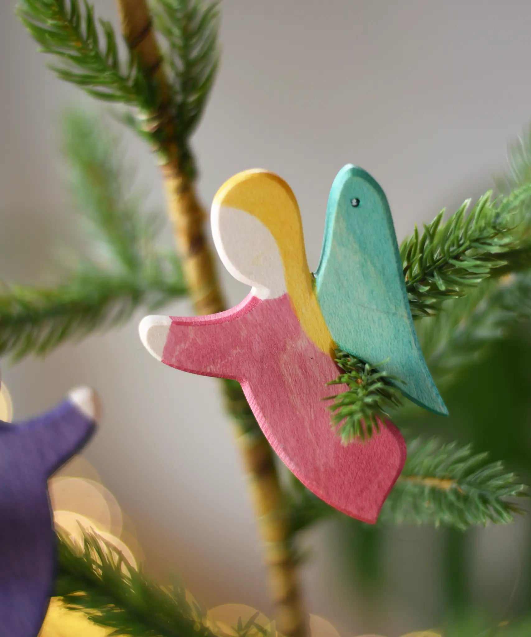 Ostheimer red angel wooden handmade decoration placed on a Christmas tree branch. 