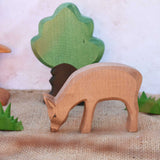 An Ostheimer red eating deer shown in a small world play scene with Ostheimer grass an Oak tree seen in the background. Check out our full range of expertly crafted wooden toy figures and scenery here at Babipur.