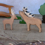 An Ostheimer male deer pictured nextto a red deer stag in a small world play scene with Ostheimer grass, oak tree and wooden toy bridge in the background. Check out our full range of expertly crafted wooden toy figures and scenery here at Babipur.