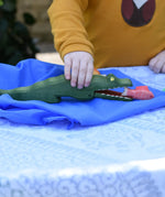 Ostheimer crocodile wooden toy figure played with by a child. Red fish has been placed in the crocodiles mouth. 