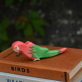 A red Ostheimer parrot placed on top of a pile of old books. 