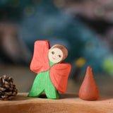 An Ostheimer hand made and hand painted wooden poppy Flower Child figure toy placed on a natural Grimm's celebration ring. These flower child wooden figures are part of a wide range of expertly hand crafted wooden toys here at Babipur. 
