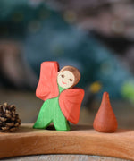 An Ostheimer hand made and hand painted wooden poppy Flower Child figure toy placed on a natural Grimm's celebration ring. These flower child wooden figures are part of a wide range of expertly hand crafted wooden toys here at Babipur. 
