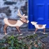 An Ostheimer reindeer and reindeer calf placed on a stone wall outdoors. Check out our full range of expertly crafted wooden toy figures and scenery here at Babipur.