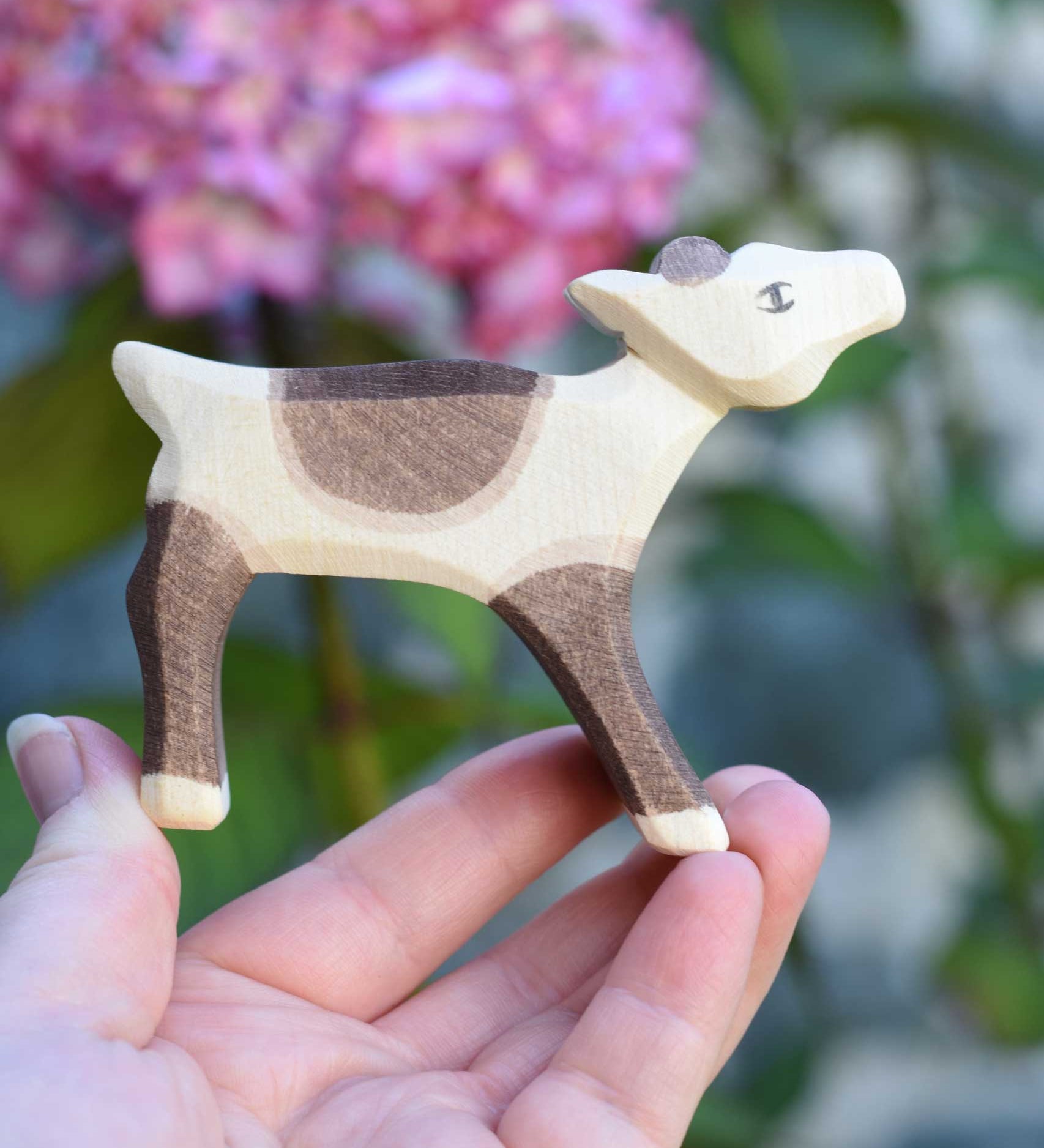 An Ostheimer reindeer calf wooden toy figure shown in an adult's hand for scale. Check out our full range of expertly crafted wooden toy figures and scenery here at Babipur.
