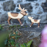An Ostheimer reindeer and reindeer calf placed next to each other on a stone wall outdoors. Check out our full range of expertly crafted wooden toy figures and scenery here at Babipur.