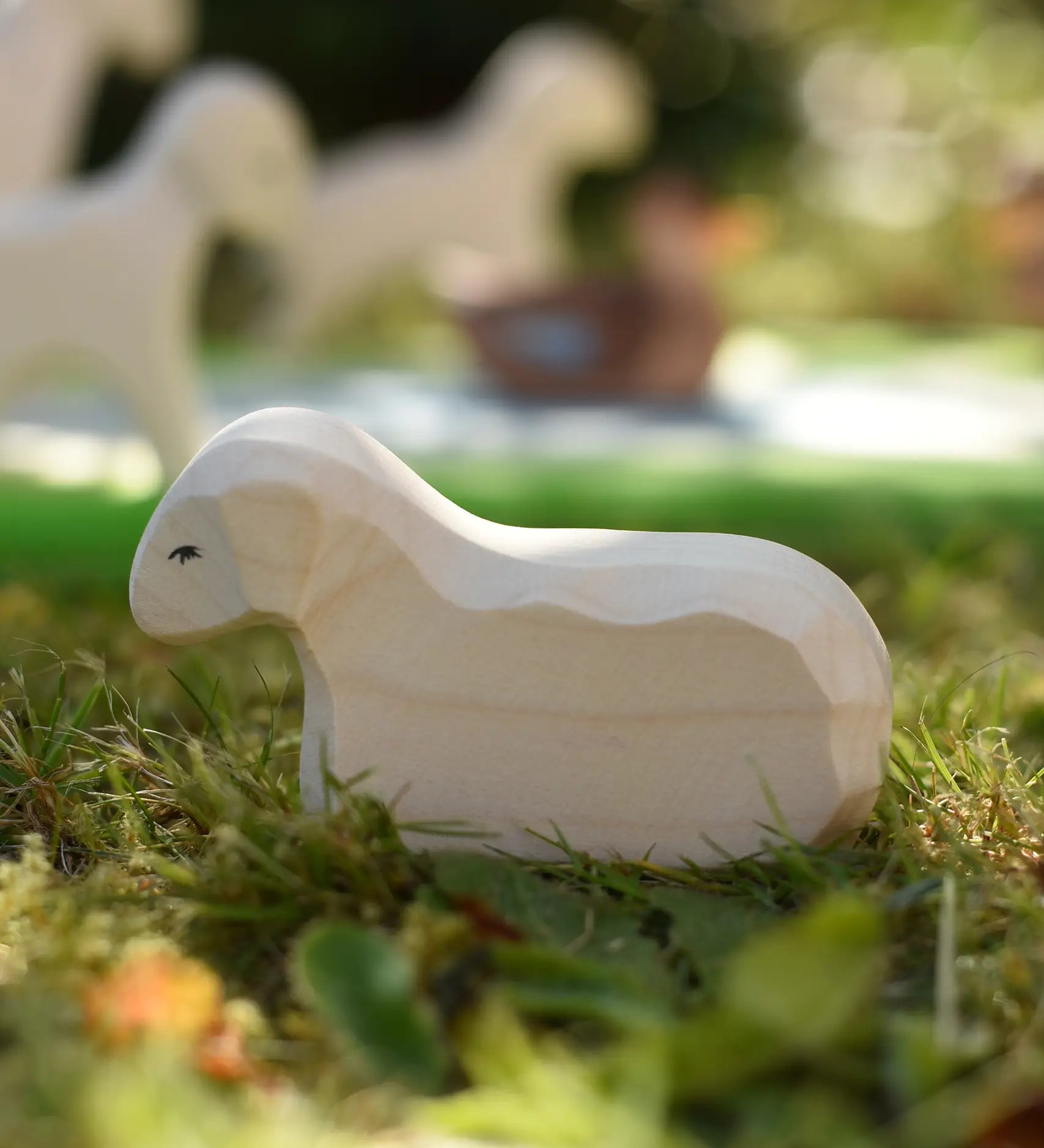 Ostheimer resting lamb wooden toy figure placed on grass in the Babipur garden.