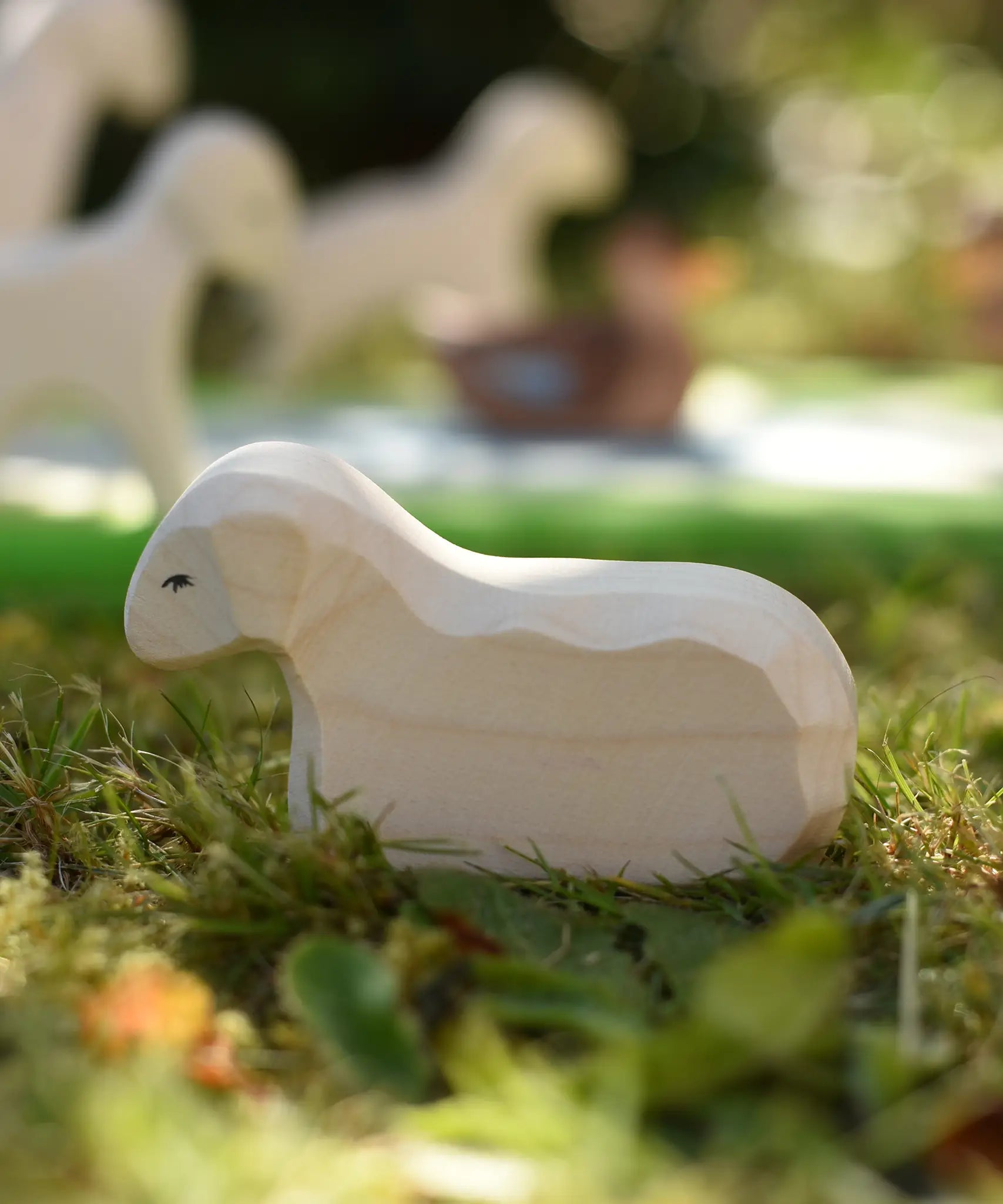 Ostheimer resting lamb wooden toy figure placed on grass in the Babipur garden.