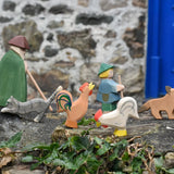 Ostheimer brown bremer and white rooster placed in a simple play scene on a stone wall outdoors. 