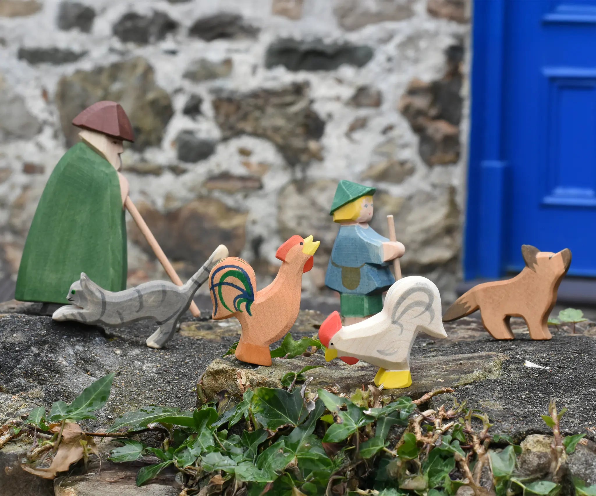 Ostheimer brown bremer and white rooster placed in a simple play scene on a stone wall outdoors. 