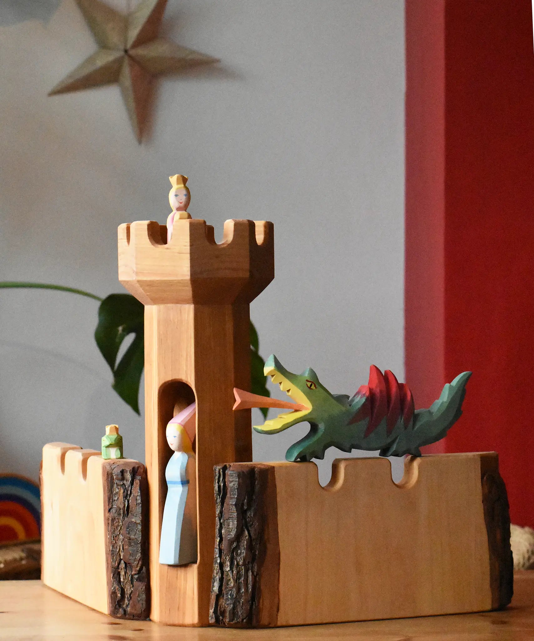 Ostheimer large wooden castle walls with a round tower in the middle. A dragon resting on one wall, frog king on the other and princesses in the tower.