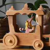 Ostheimer Wooden Stage Coach toy with princess figures placed inside and a child playing in the background.