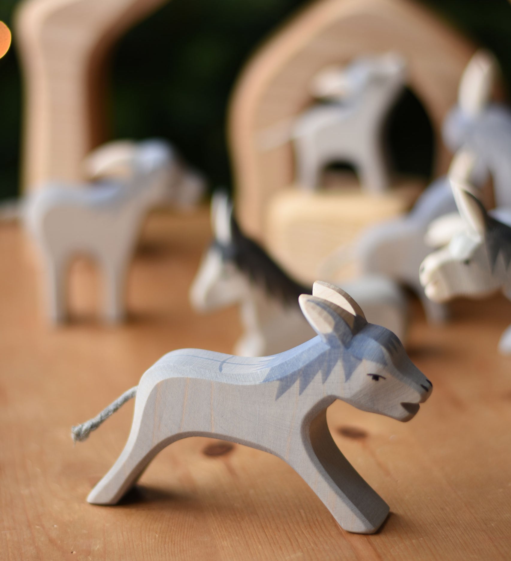 Ostheimer running donkey wooden toy figure placed on a wooden surface with other donkeys in the background.  Ostheimer's range of hand crafted, heirloom quality wooden toys are available to buy at Babipur. 