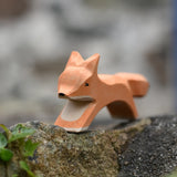 Ostheimer running fox wooden toy figure placed on a stone wall outdoors. 