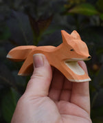 Ostheimer running fox wooden toy figure in an adult's hand.