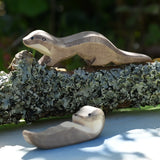 Ostheimer running sea otter wooden toy figure placed on a lichen covered branch. 