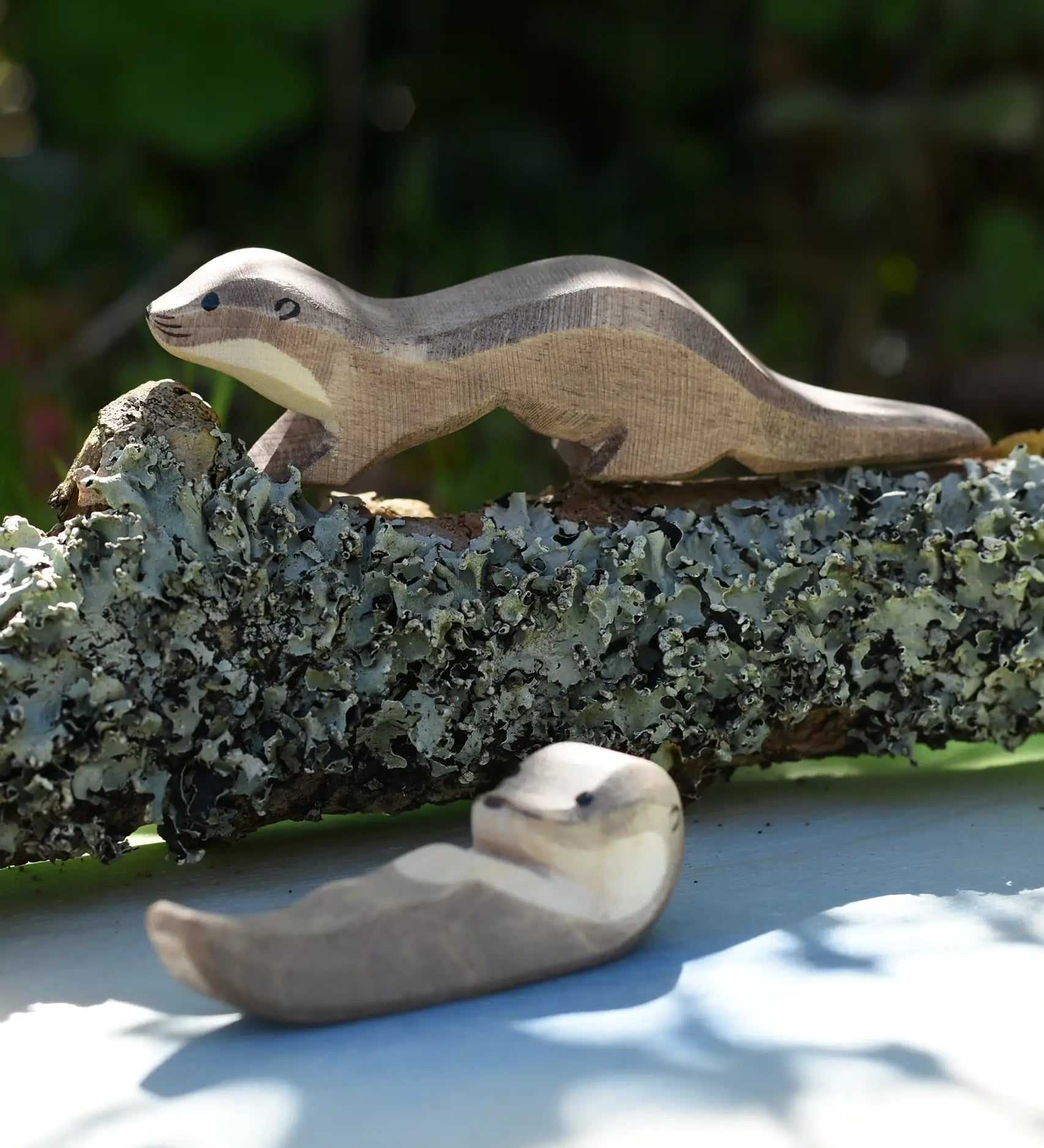 Ostheimer running sea otter wooden toy figure placed on a lichen covered branch. 