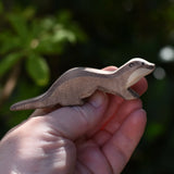 Ostheimer running sea otter wooden toy figure in an adult's hand.