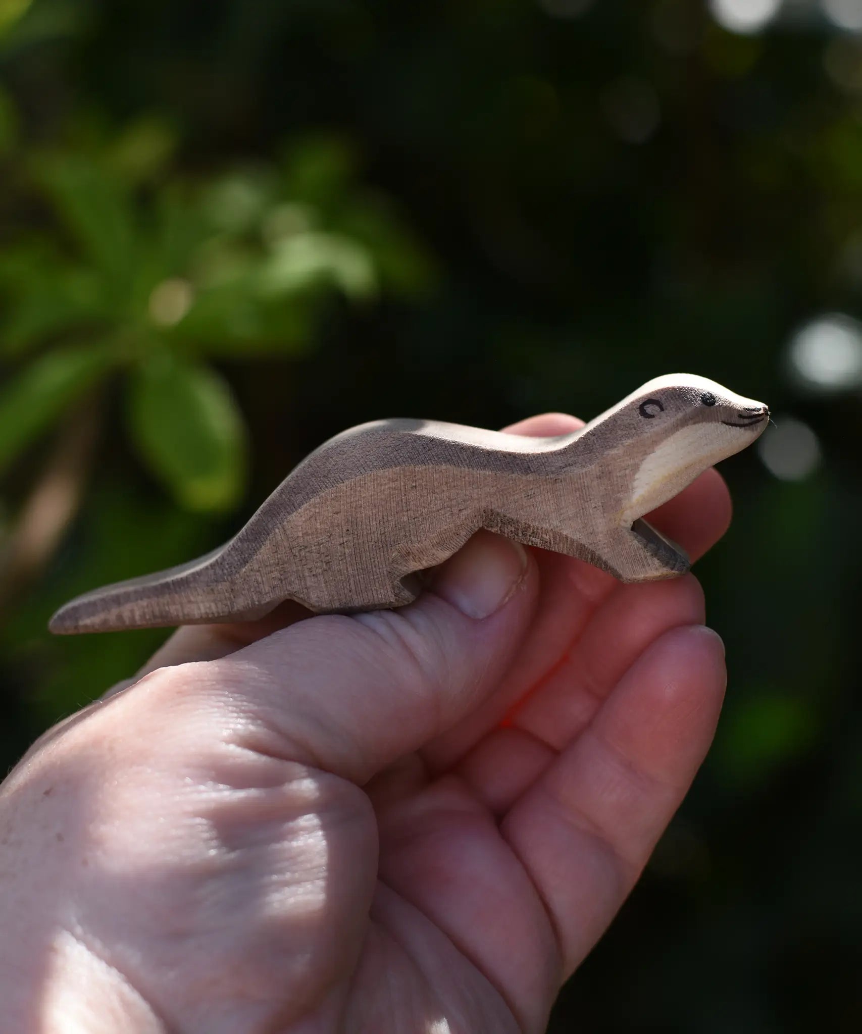 Ostheimer running sea otter wooden toy figure in an adult's hand.