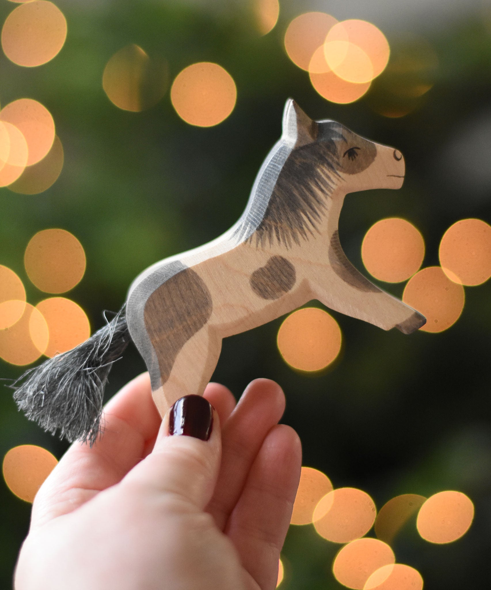 An Ostheimer shetland pony wooden toy figure in an adult's hand.  Ostheimer's range of hand crafted, heirloom quality wooden toys are available to buy at Babipur. 