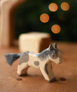 An Ostheimer shetland pony wooden toy figure placed on a wooden surface.  Ostheimer's range of hand crafted, heirloom quality wooden toys are available to buy at Babipur. 