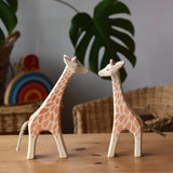 Ostheimer running and standing giraffes wooden toy figures placed on a wooden surface. 