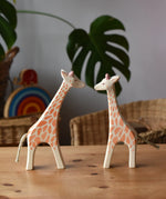 Ostheimer running and standing giraffes wooden toy figures placed on a wooden surface. 