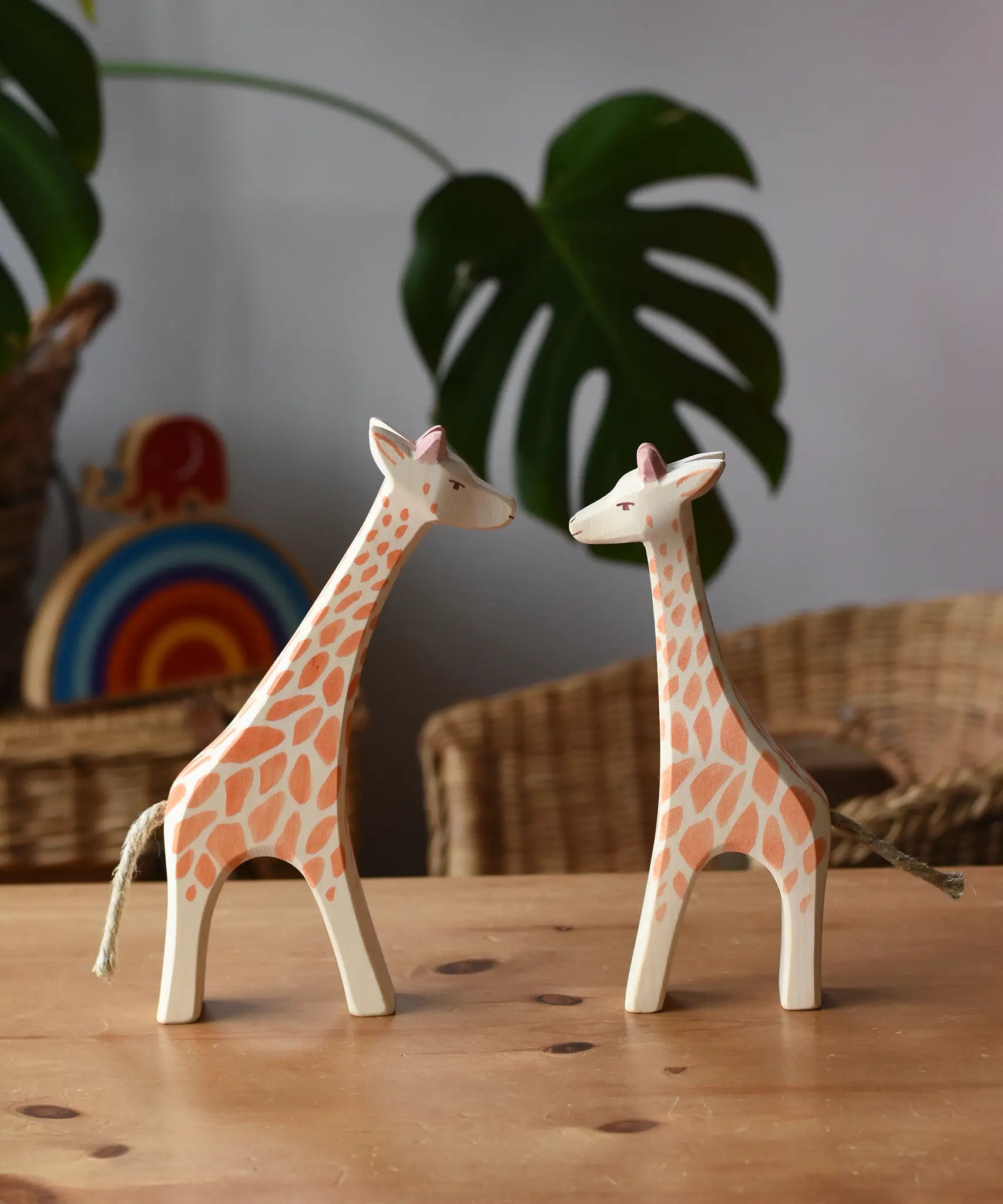 Ostheimer running and standing giraffes wooden toy figures placed on a wooden surface. 