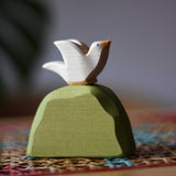 Ostheimer white dove bird figure placed on a middle green bush. 