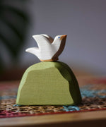 Ostheimer white dove bird figure placed on a middle green bush. 