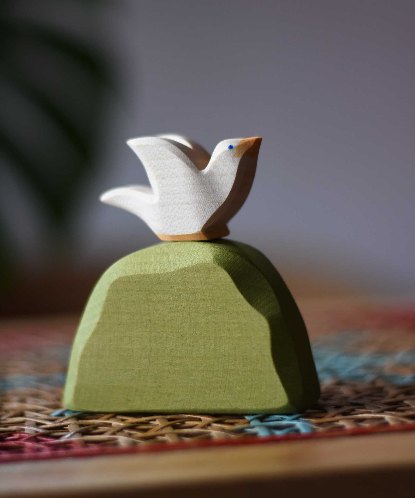 Ostheimer white dove bird figure placed on a middle green bush. 