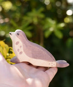Ostheimer sea lion wooden toy figure with it's had low in an adult's hand.