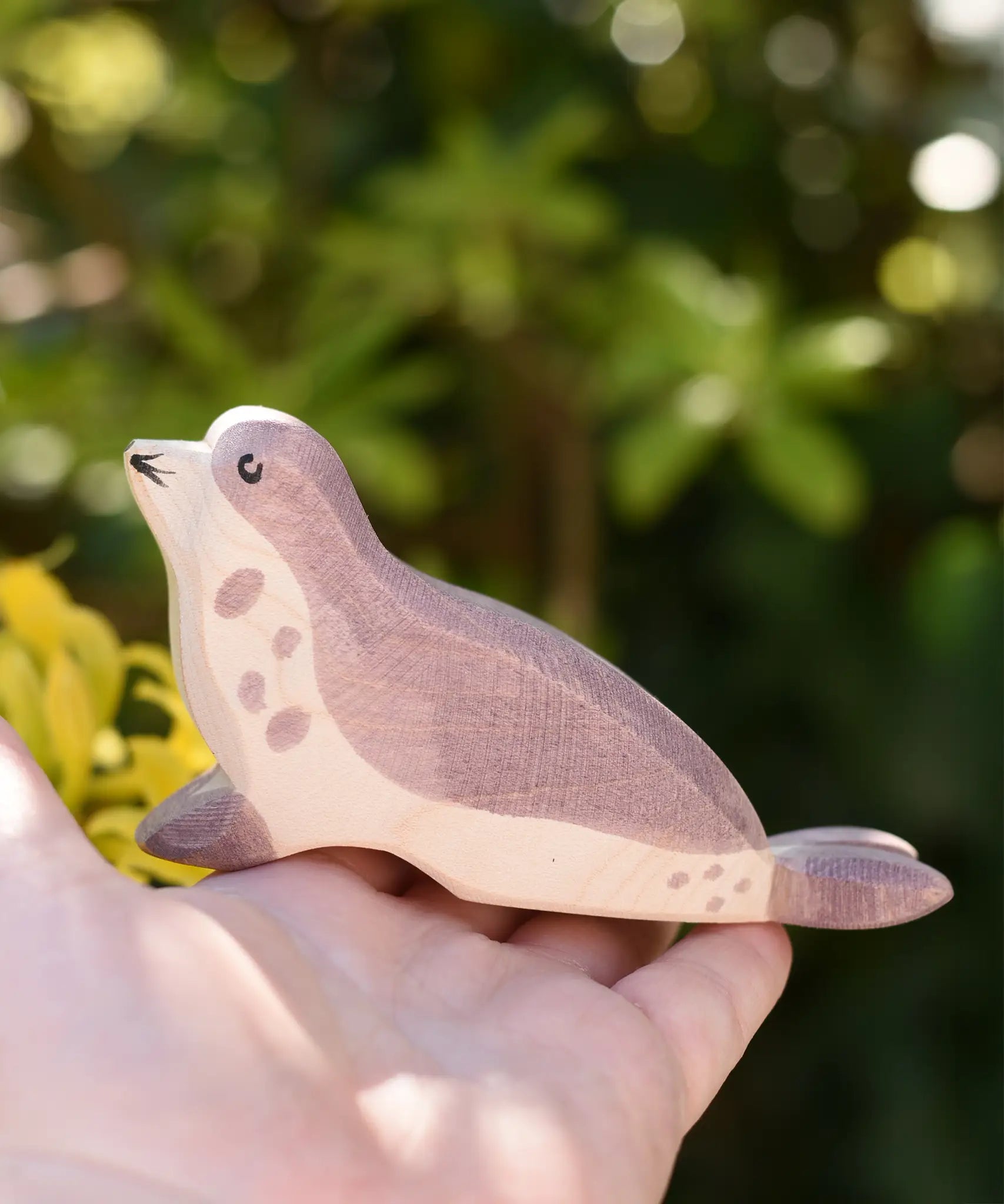 Ostheimer sea lion wooden toy figure with it's had low in an adult's hand.