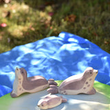 Ostheimer small sea lion pup, head high and head low wooden toy figures placed on a pond piece on blue Laura's cotton play cloth in the Babipur garden.