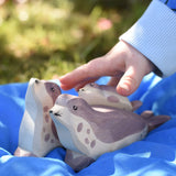 Ostheimer small sea lion pup wooden toy figure placed on the back of a bigger sea lion on a blue Laura's cotton play cloth in the Babipur garden.
