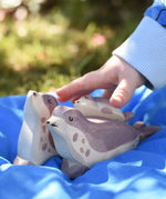 Ostheimer small sea lion pup wooden toy figure placed on the back of a bigger sea lion on a blue Laura's cotton play cloth in the Babipur garden.