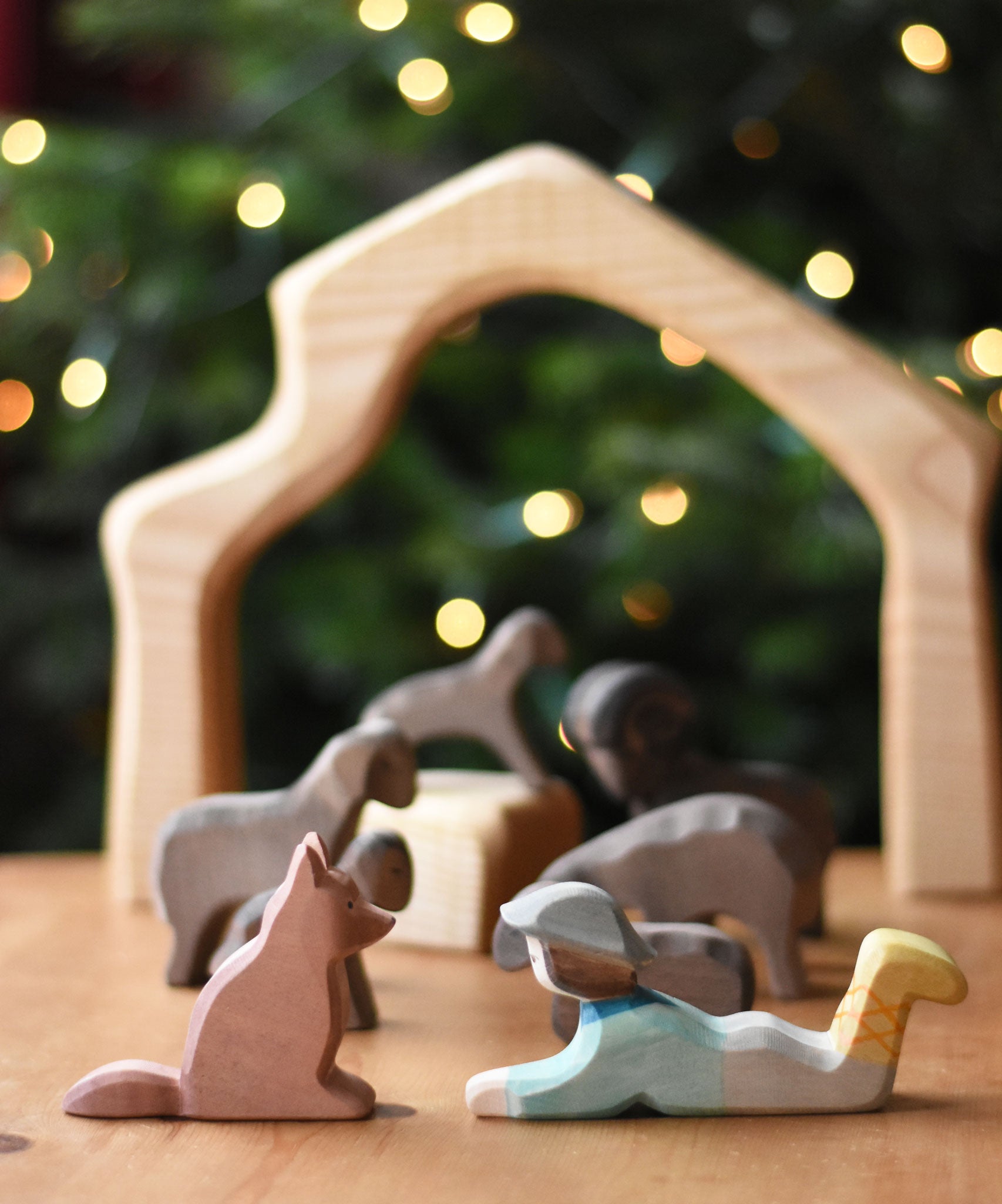 An Ostheimer shepherd's dog wooden toy figure and a lying shepherd figure placed on a wooden surface. These wooden figures are part of a wide range of expertly hand crafted wooden toys here at Babipur. 