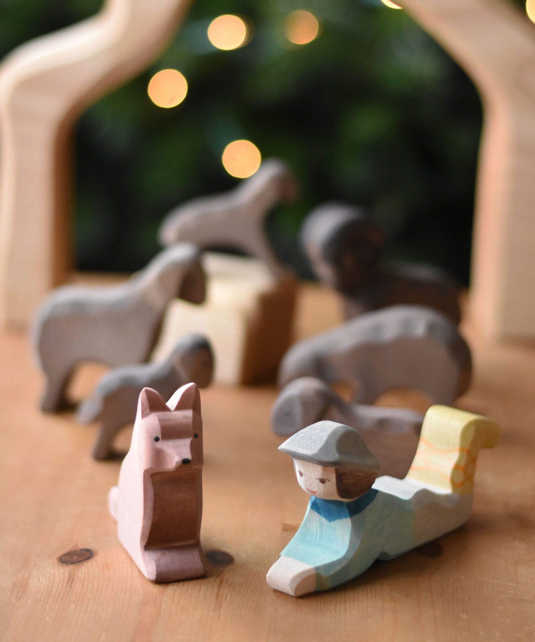 An Ostheimer shepherd's dog wooden toy figure and a lying shepherd figure placed on a wooden surface. These wooden figures are part of a wide range of expertly hand crafted wooden toys here at Babipur. 