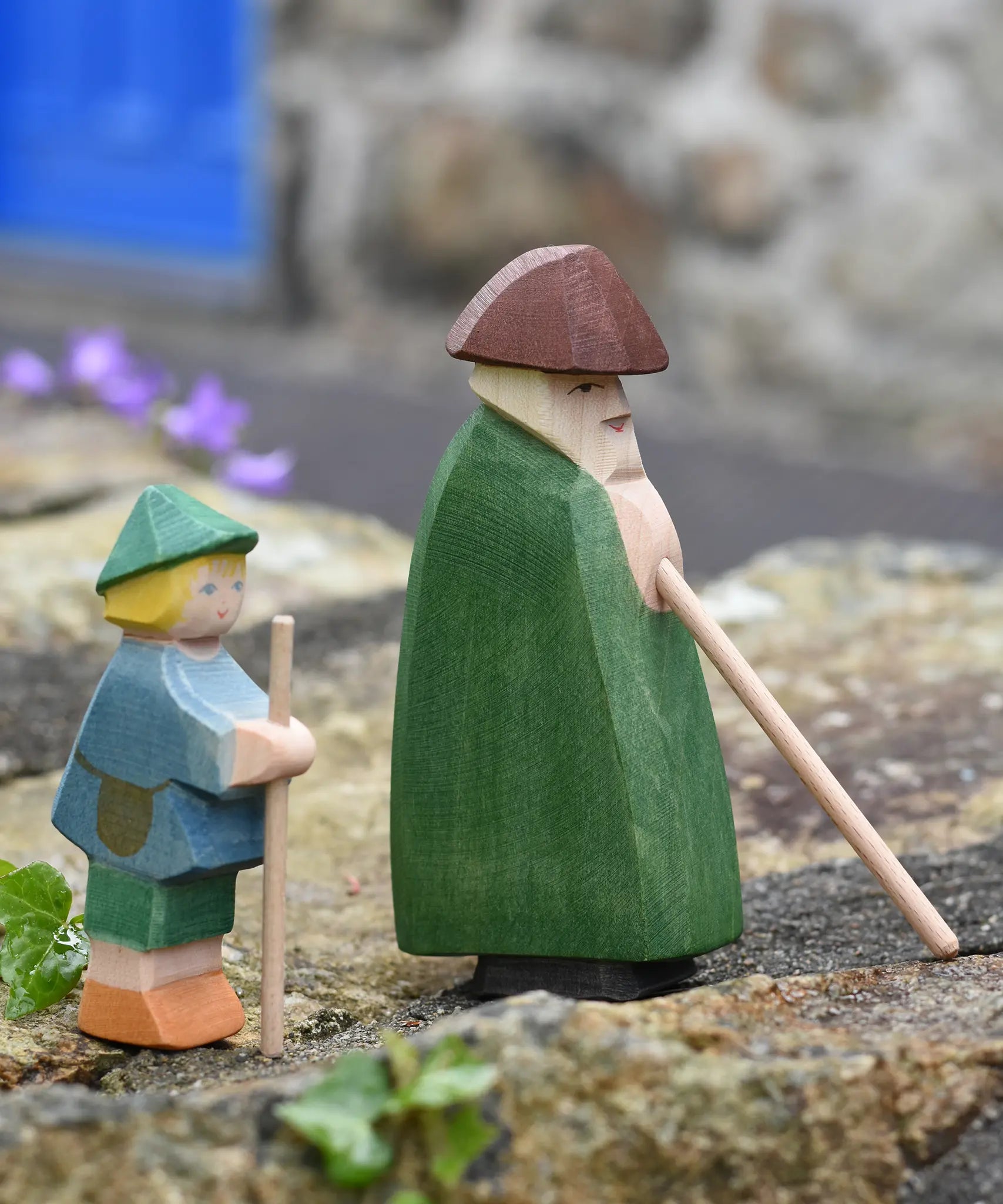 Ostheimer shepherd with staff next to a small shepherd boy placed on a stone wall outdoors. 