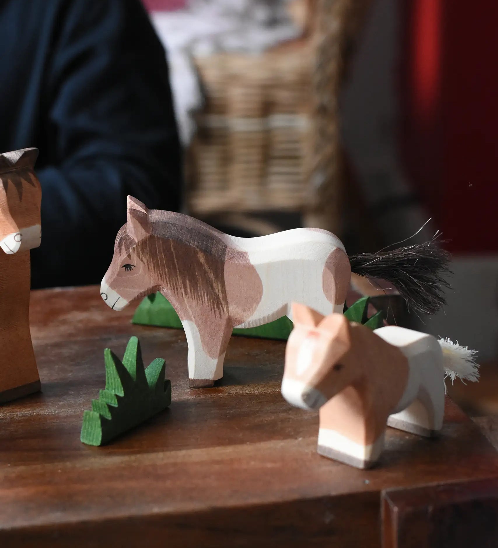 Ostheimer Shetland pony standing wooden toy figure in a small world play scene with other horse figures and green grass. 