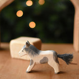 An Ostheimer shetland pony wooden toy figure placed on a wooden surface.  Ostheimer's range of hand crafted, heirloom quality wooden toys are available to buy at Babipur. 