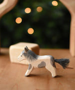 An Ostheimer shetland pony wooden toy figure placed on a wooden surface.  Ostheimer's range of hand crafted, heirloom quality wooden toys are available to buy at Babipur. 