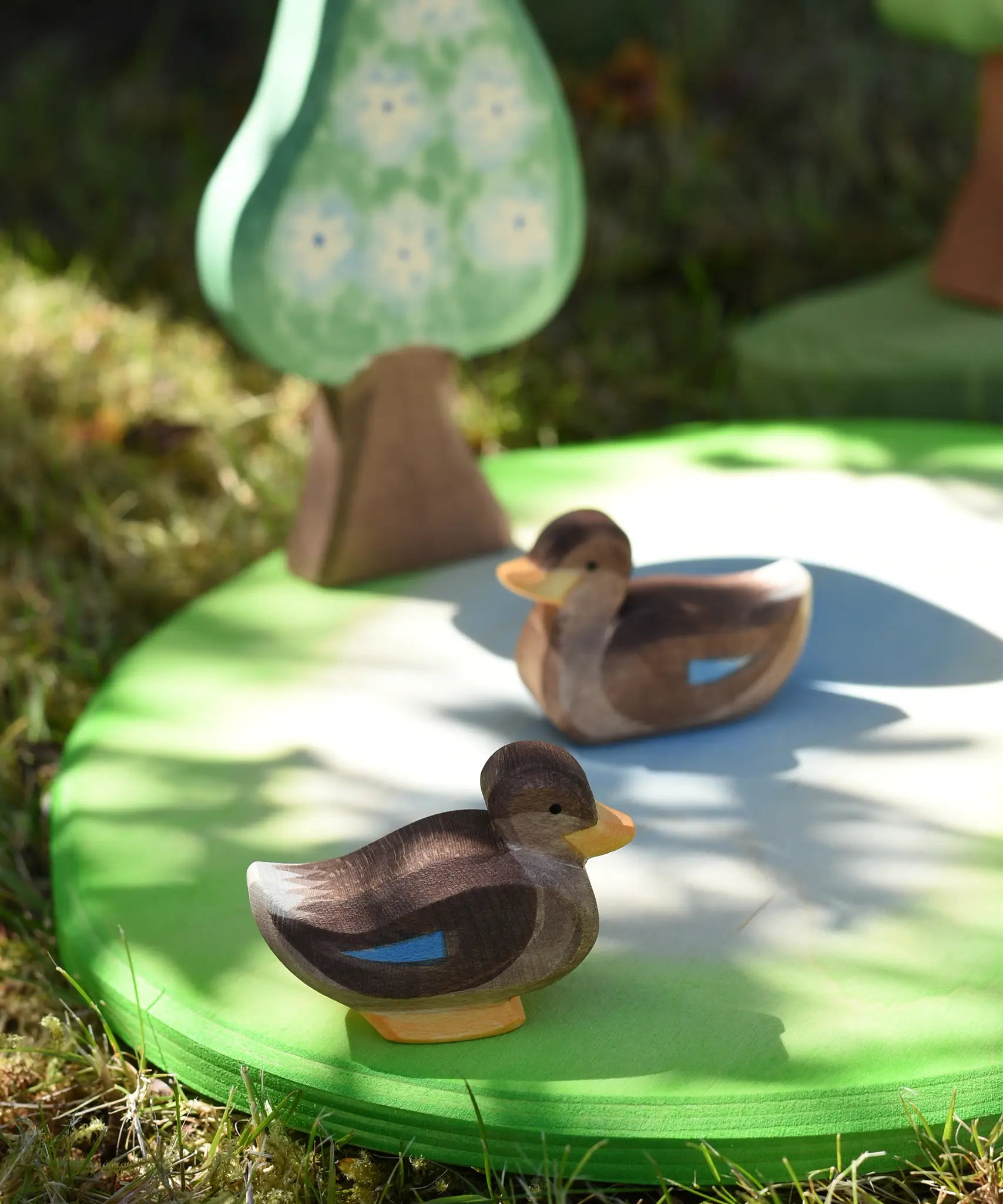 Ostheimer swimming and sitting duck wooden toy figures placed on a pond piece in the Babipur garden. 