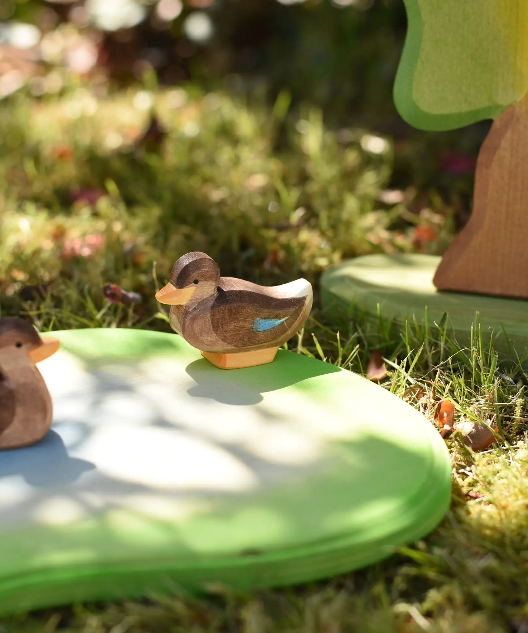 Ostheimer sitting duck wooden toy figure placed on a pond piece in the Babipur garden. 
