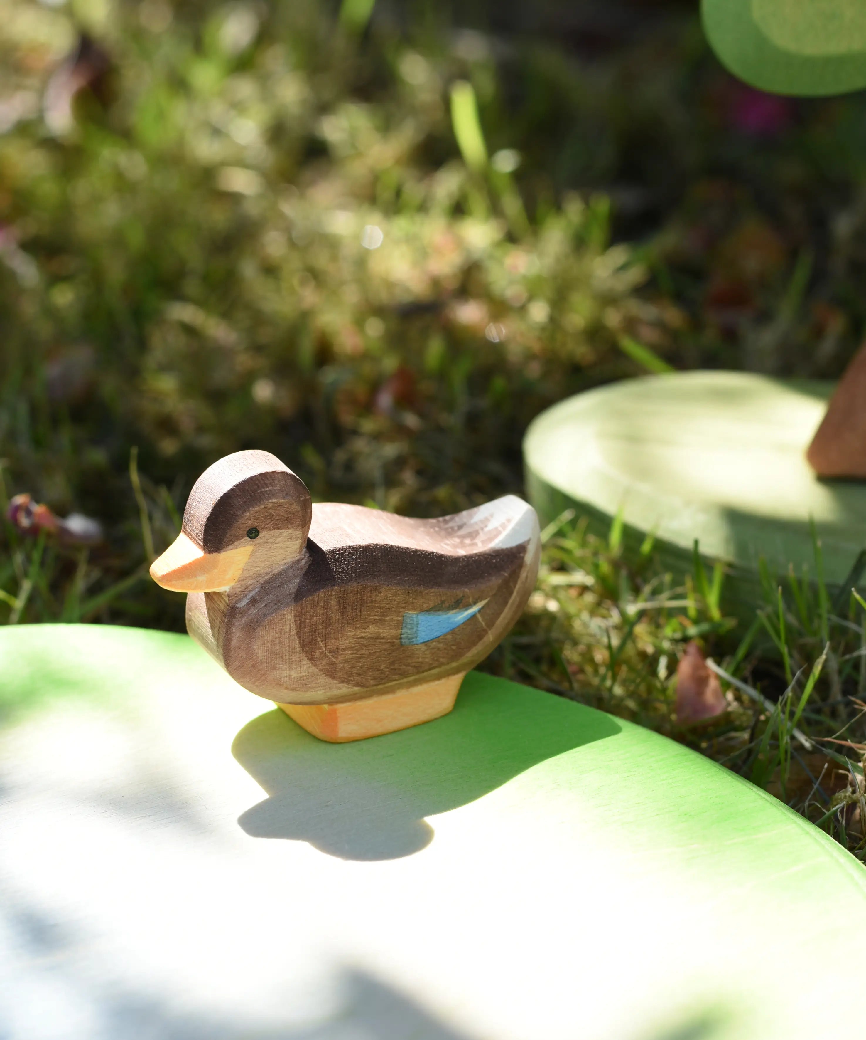 Ostheimer sitting duck wooden toy figure placed on a pond piece in the Babipur garden. 