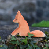 An Ostheimer sitting red fox toy figure placed on a stone wall outdoors. Check out our full range of expertly crafted wooden toy figures and scenery here at Babipur.