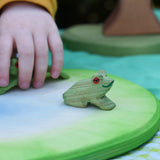 Ostheimersitting frog handmade wooden toy figure placed on a pond piece.