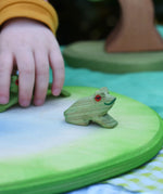 Ostheimersitting frog handmade wooden toy figure placed on a pond piece.