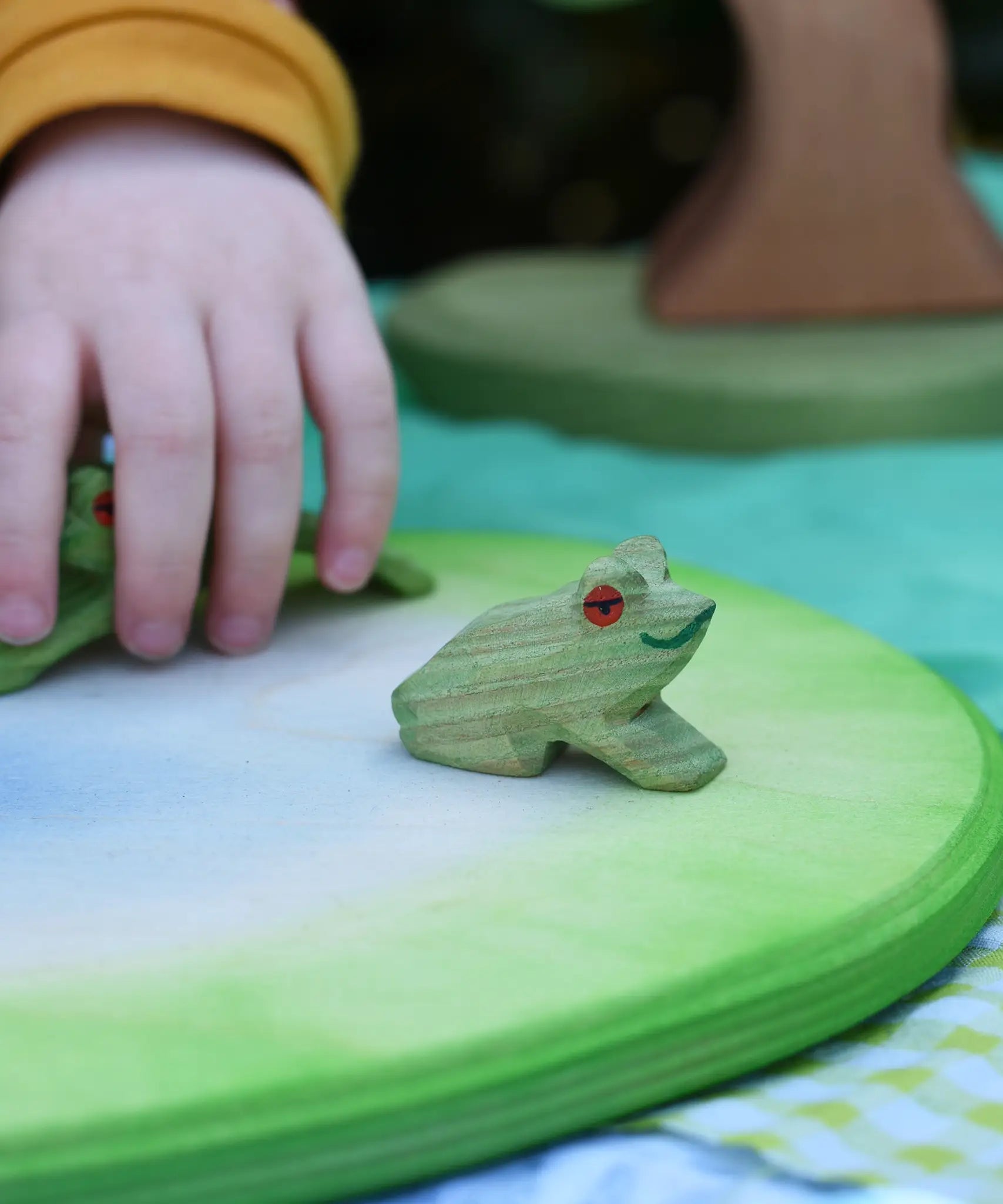 Ostheimersitting frog handmade wooden toy figure placed on a pond piece.